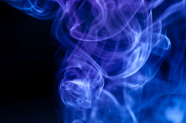 Abstract blue smoke over black background .