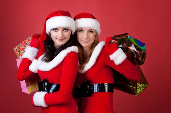 Duas mulheres em vestem de Papai Noel, com sacos de compras — Fotografia de Stock