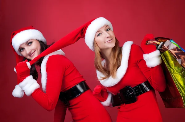 Duas mulheres em vestem de Papai Noel, com saco de compras — Fotografia de Stock