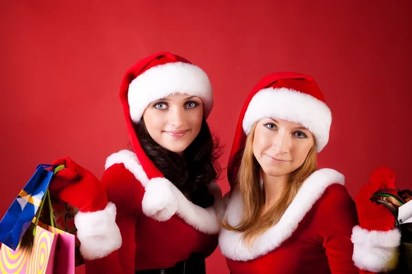 Dos mujeres en vestidos de Papá Noel, con bolsas de compras —  Fotos de Stock