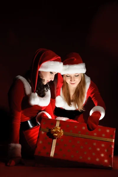 Dvě ženy v kostýmu santa otevírání vánoční dárek. — Stock fotografie
