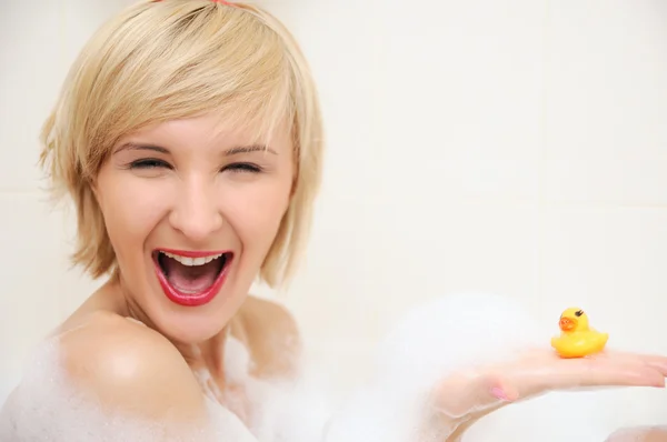 Femme blonde souriante se situant dans le bain moussant — Photo