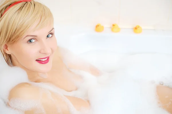 泡風呂で横になっている笑顔金髪の女性 — ストック写真