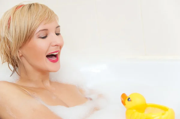 Femme blonde souriante se situant dans le bain moussant — Photo