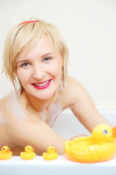 Usměvavá blondýnka ležící v bublinkové lázni — Stock fotografie