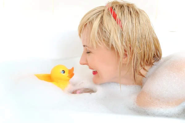 Mulher loira sorridente mentindo em banho de espuma — Fotografia de Stock