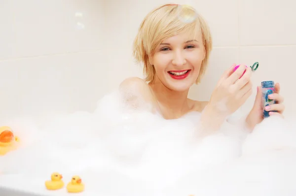 Uśmiechający się blond kobieta leżący w bubble bath — Zdjęcie stockowe