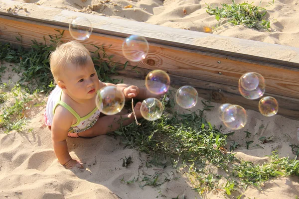 Curious baby looking at soap bubbles — Stock Photo, Image