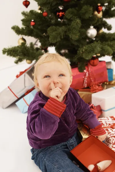 Bebê sorrateiramente abrir presente de Natal — Fotografia de Stock
