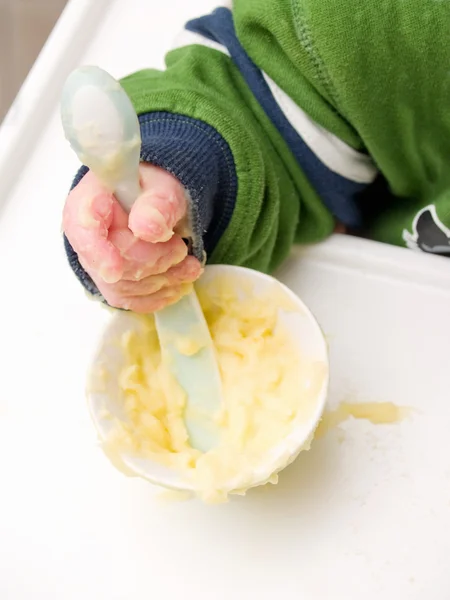 La mano del bebé usando cuchara para comer — Foto de Stock