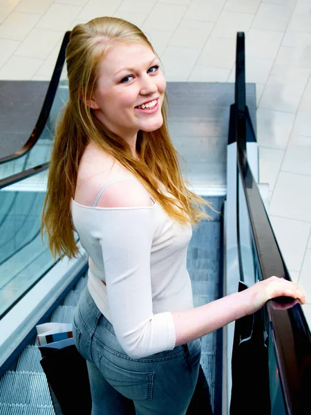 Sorrindo jovem comprador na escada rolante — Fotografia de Stock