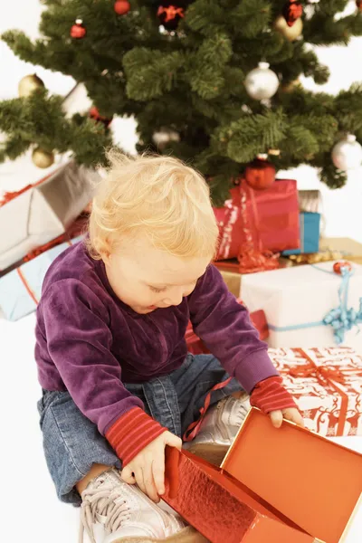 打开圣诞礼物的惊讶的孩子 免版税图库图片