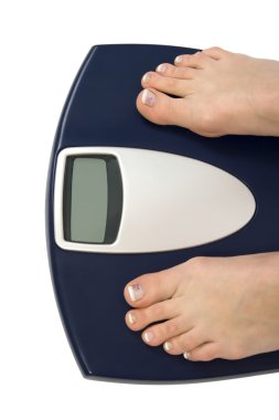 Female feet standing on a bathroom scale clipart