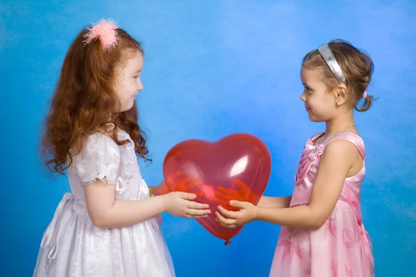 Dvě malá holčička drží červený balónek — Stock fotografie