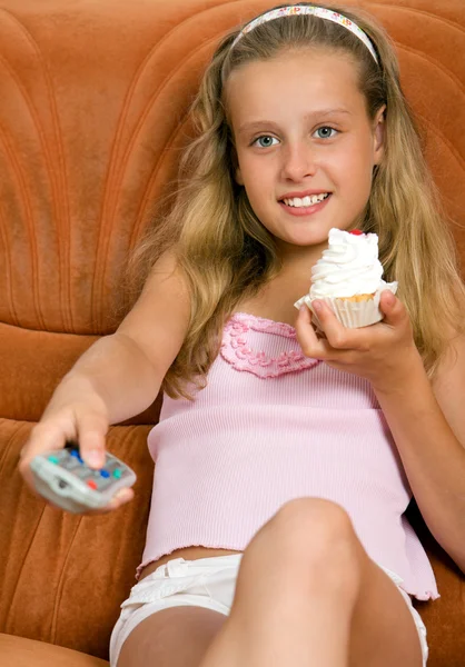 Child watching tv and eating cake — Stock Photo, Image