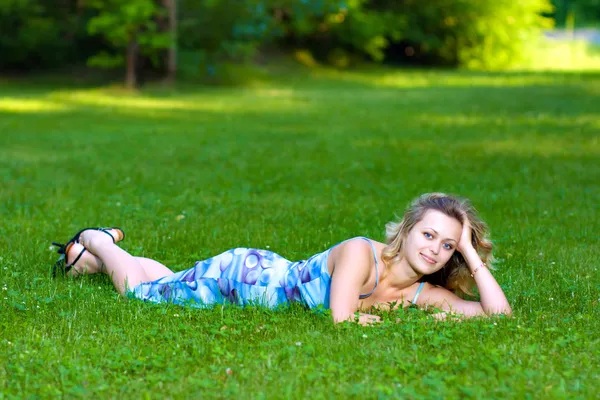 Jovem deitada em uma grama verde — Fotografia de Stock
