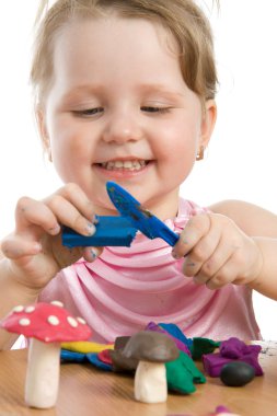 Girl playing with color play plasticine clipart