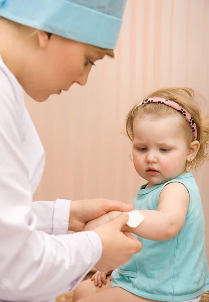 Médico colocando uma bandagem em um braço de criança — Fotografia de Stock