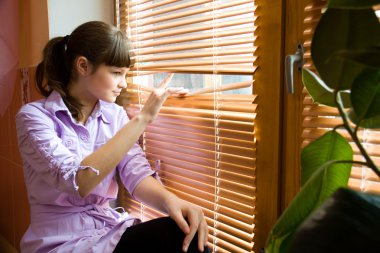 Beautiful girl looks out of the window clipart