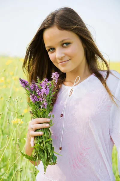Jong meisje met bloemen op een weide — Stockfoto