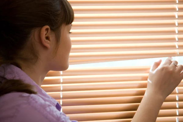 Nastolatka dziewczyny wygląda przez okno — Zdjęcie stockowe