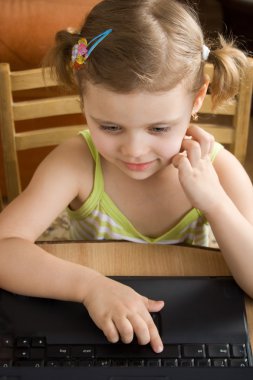 Little girl working with a laptop clipart