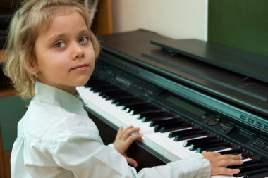 Little girl play on a electric piano clipart