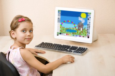 Little girl draws at the computer clipart