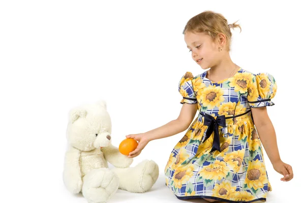 Kislány, a narancs és a medve-játék. — Stock Fotó