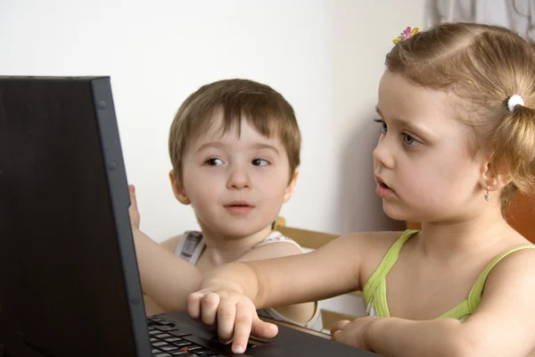 Irmã e irmão trabalhando com um laptop — Fotografia de Stock