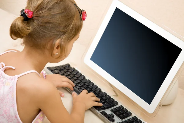 Liten flicka att skriva text på datorn — Stockfoto