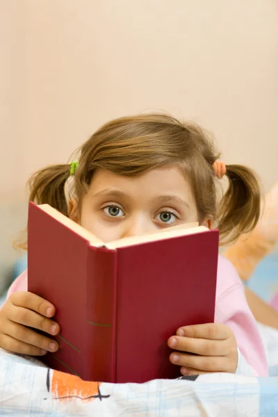 Молодая девушка читает книгу на кровати — стоковое фото