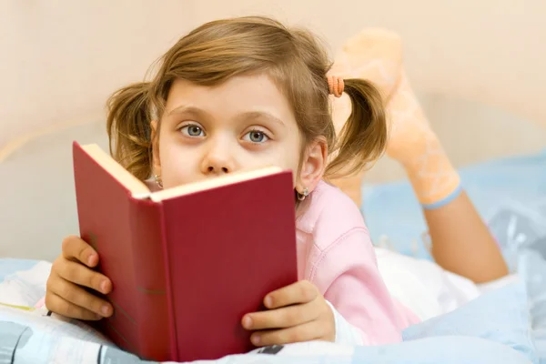 Młoda dziewczyna, czytając książkę na łóżko — Zdjęcie stockowe