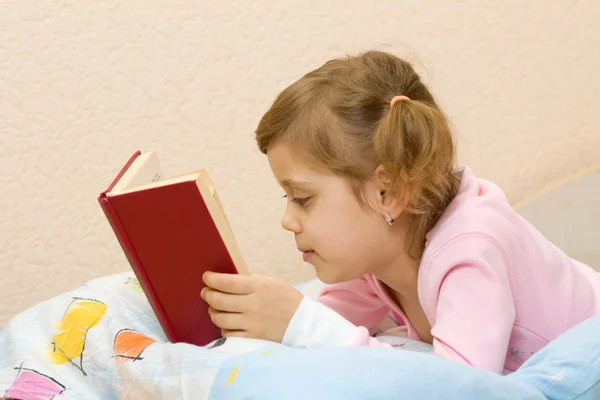 Ung flicka som läser en bok på sängen — Stockfoto
