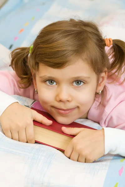 Ung flicka som läser en bok på sängen — Stockfoto