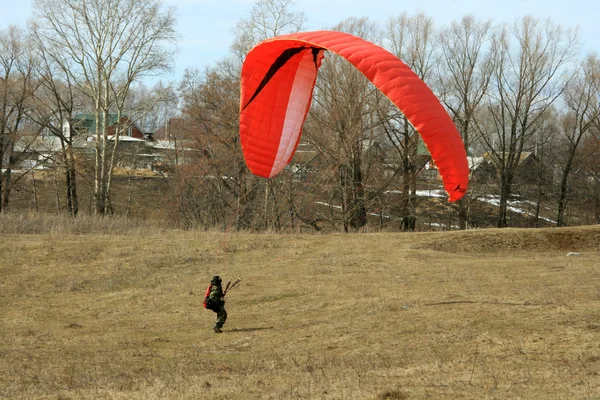 一个红色的滑翔伞的着陆 免版税图库照片