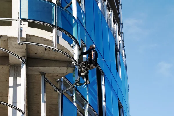 Builder fixing glass on tall building — Stock Photo, Image
