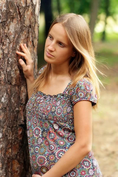 Junge Frau berührt Baum — Stockfoto