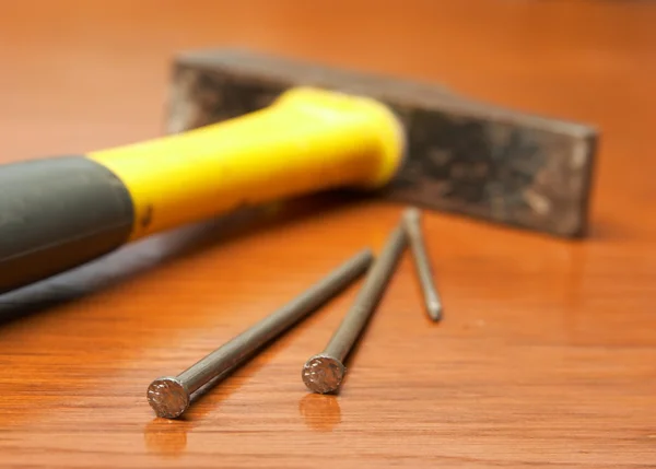 De hamer, spijkers liggen op een houten tafel — Stockfoto