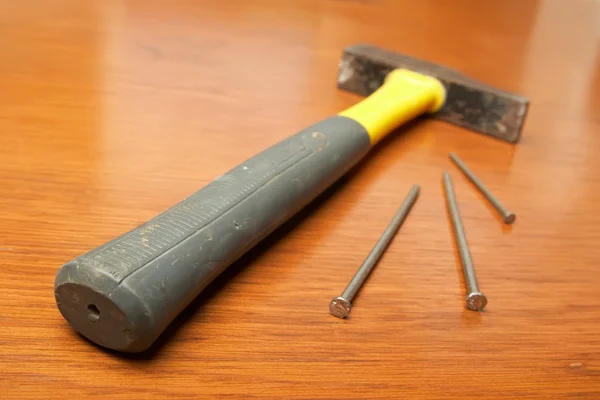 De hamer, spijkers liggen op een houten tafel — Stockfoto