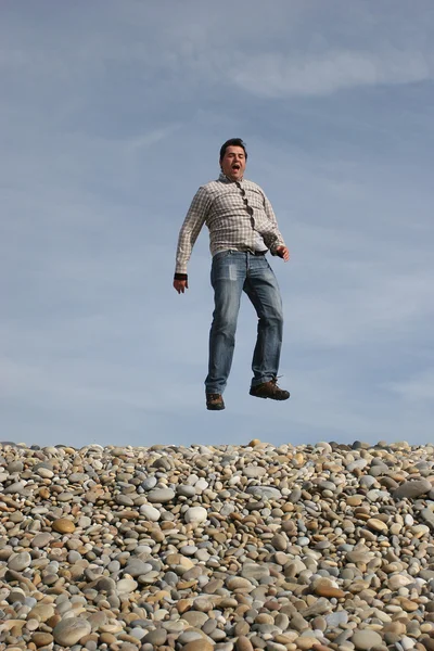 若いカジュアルな男がビーチでジャンプ — ストック写真