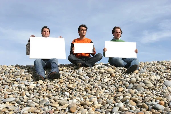 Homens segurando cartão branco na praia — Fotografia de Stock