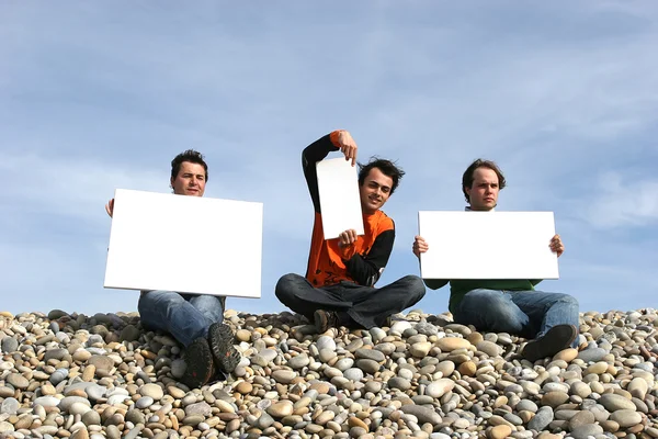 Män innehar vitt kort på stranden — Stockfoto