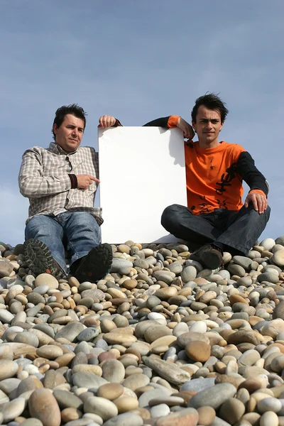 Мужчины держат белую карту на пляже — стоковое фото