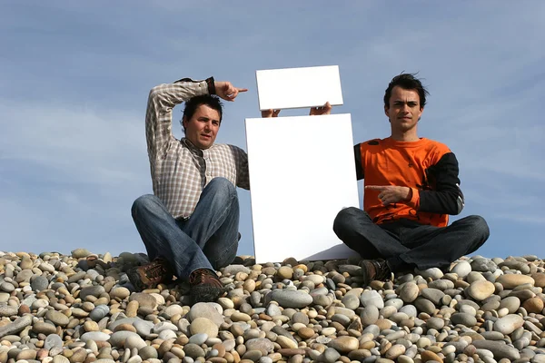 Mężczyźni posiadający białe karty na plaży — Zdjęcie stockowe