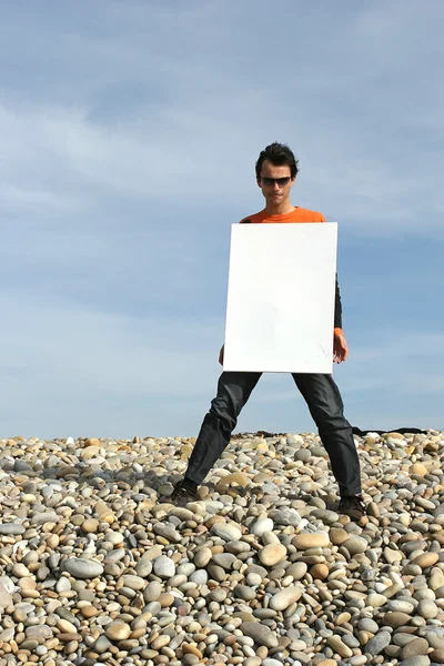 Homme tenant une carte blanche à la plage — Photo