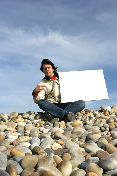Чоловік тримає білу картку на пляжі — стокове фото