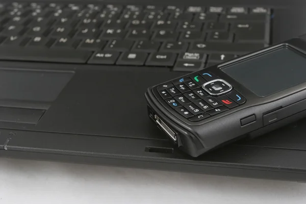 Мобильный телефон изолирован на клавиатуре ноутбука — стоковое фото