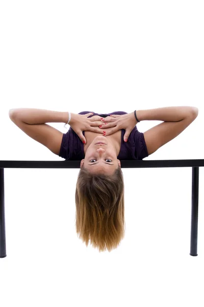 Junge Frau posiert kopfüber auf einem Schreibtisch — Stockfoto