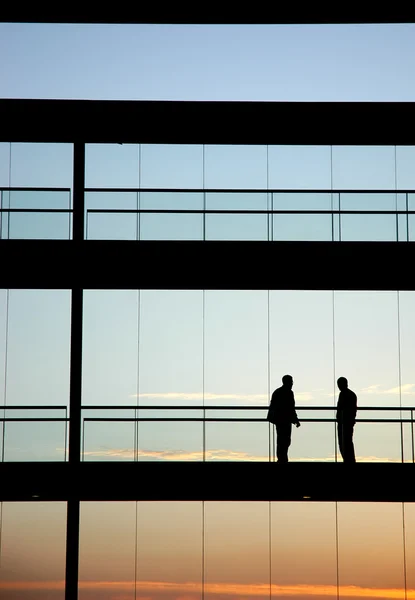 Két munkavállalók belsejében az épület sziluett naplementekor — Stock Fotó